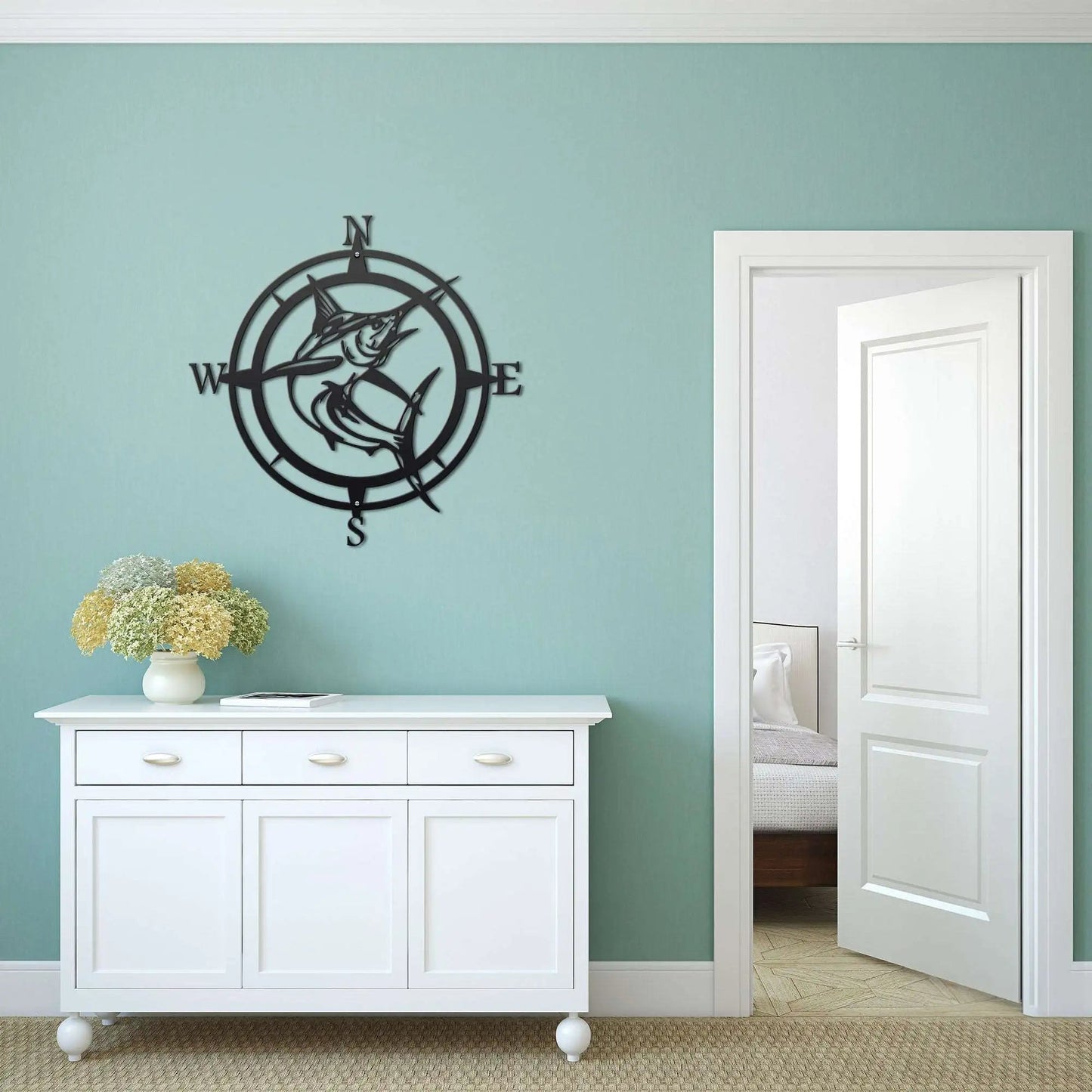 Decorative metal wall compass on light blue wall above white cabinet with flowers, nautical home décor, custom indoor wall art