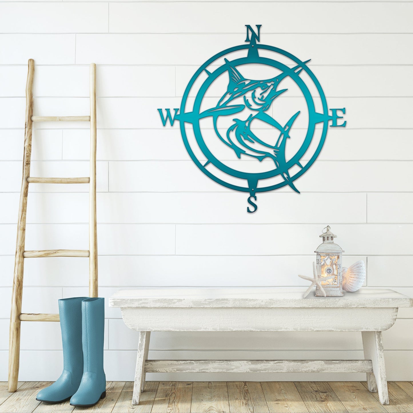 Teal compass wall decor with dolphins on white wall with wooden floor and ladder, nautical-themed home décor, decorative metal wall art
