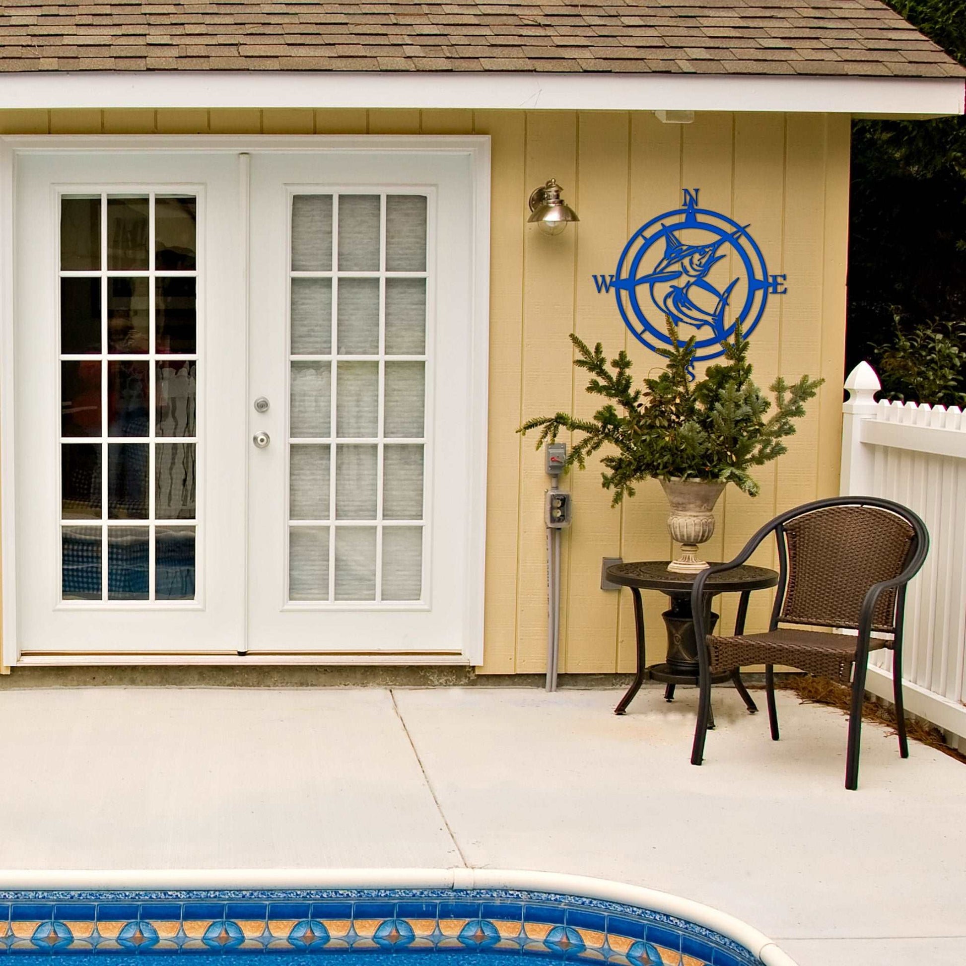 Outdoor patio area with pool, chairs, table, and decorative accents on house exterior, featuring custom outdoor décor and relaxing backyard setup