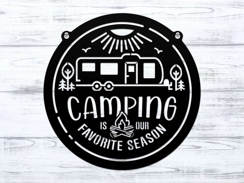 Circular metal sign featuring a camping-themed design with text, displayed on a white wooden background, highlighting rustic style and durable decorative craftsmanship.