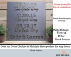 Decorative metal sign featuring engraved dates and names, displayed on a wooden surface with plants, highlighting personalized design, rustic charm, and durable craftsmanship.