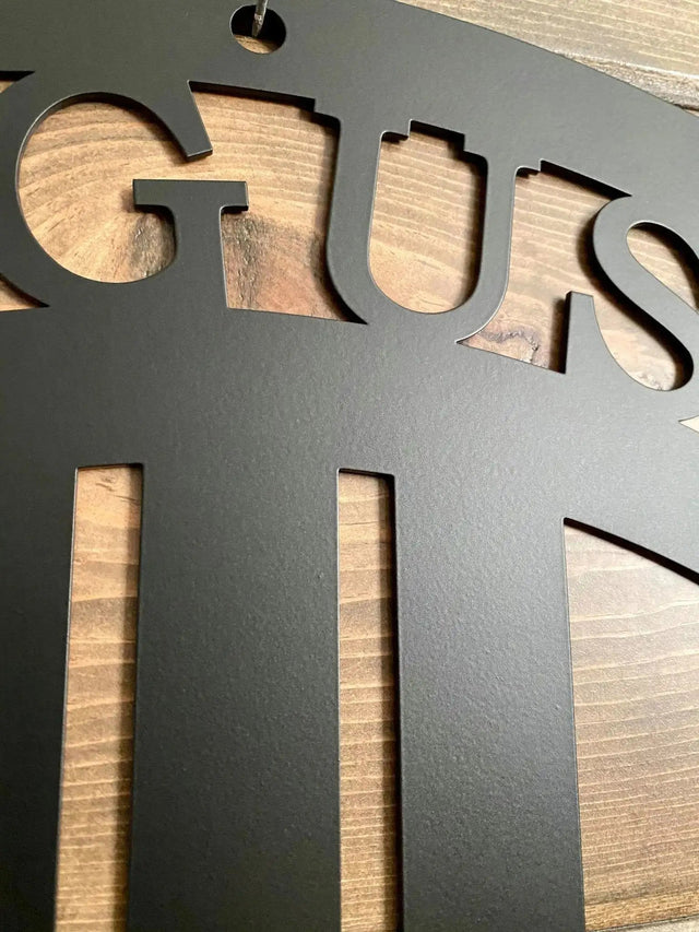 Close-up of black mustang sign showing laser-cut “GUS” text detail and metal texture, highlighting precision cut.