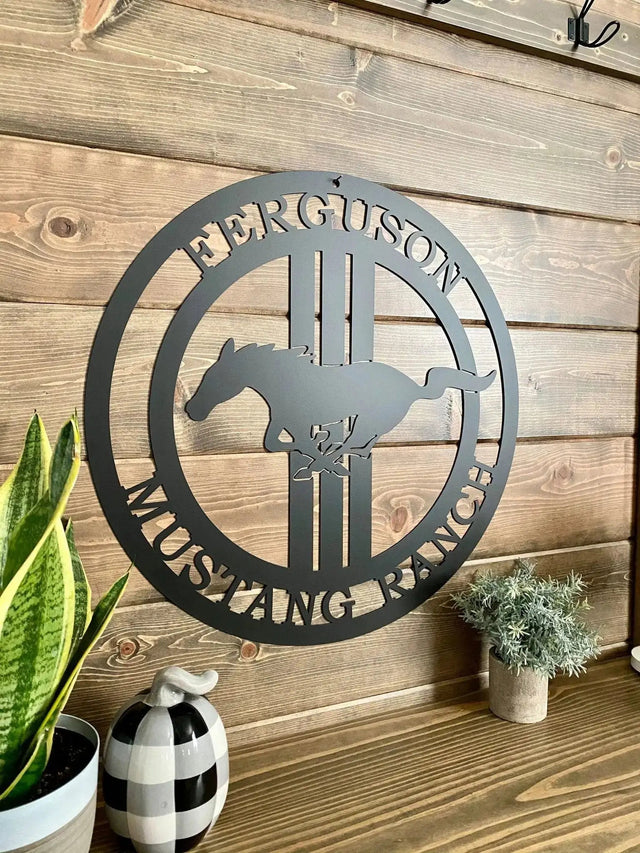 Side view of black custom laser cut ranch sign with mustang silhouette and “FERGUSON MUSTANG RANCH” text, on rustic wood