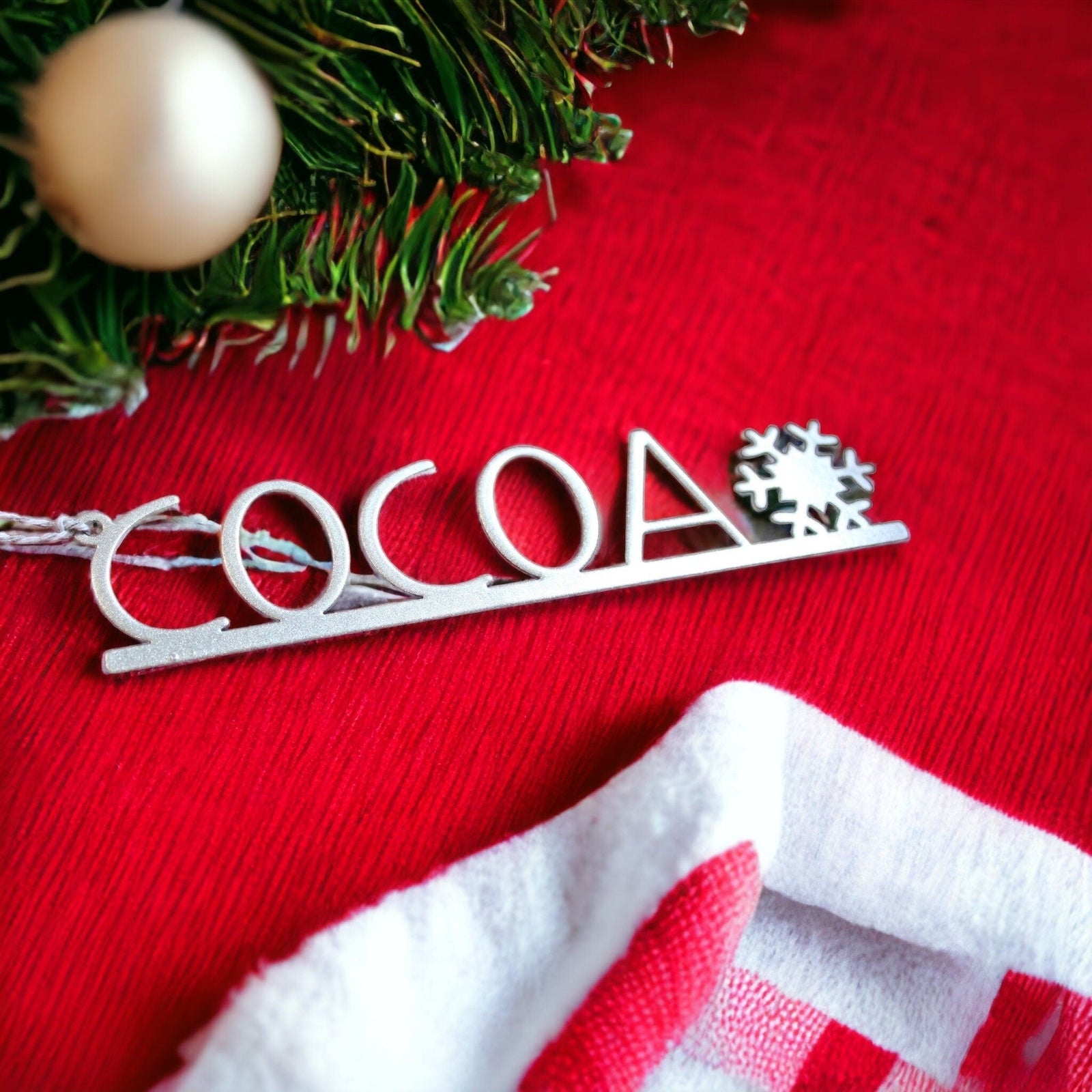 Personalized snowflake metal name tag with COCOA text, custom Christmas table décor place setting, laser cut holiday ornament on red festive background, HouseSensationsArt