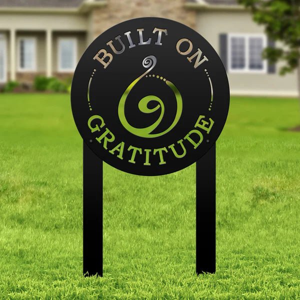 Decorative metal sign with Built on Gratitude text on a grassy lawn, personalized outdoor signage for home décor and garden display