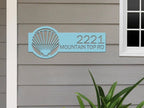 Metallic blue seashell address sign on house exterior, personalized house numbers, coastal front door décor, outdoor nautical plaque.
