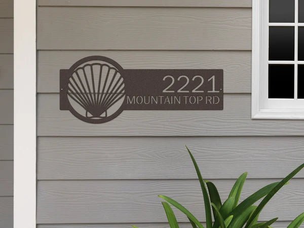 Seashell house number sign on house exterior, personalized metal address plaque, coastal front door décor, outdoor nautical home sign.