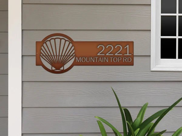 Seashell house number sign on house exterior, personalized metal address plaque, coastal front door décor, outdoor nautical home sign.