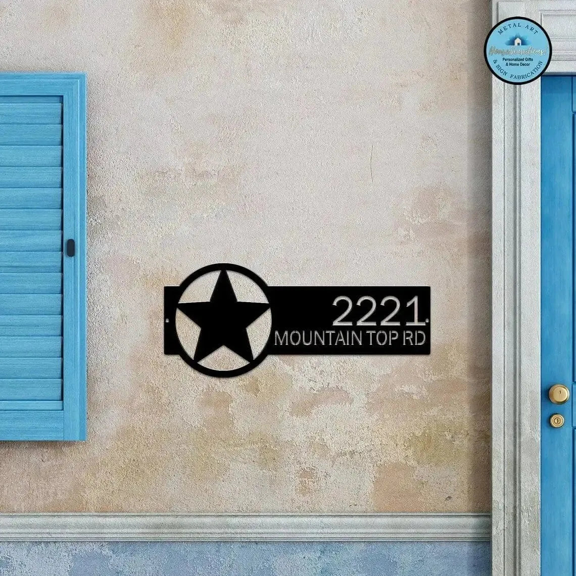Black Star Monogram Address Sign featuring a star emblem on the right and house number '2221 Mountain Top Rd' on the left, mounted on a beige wall.