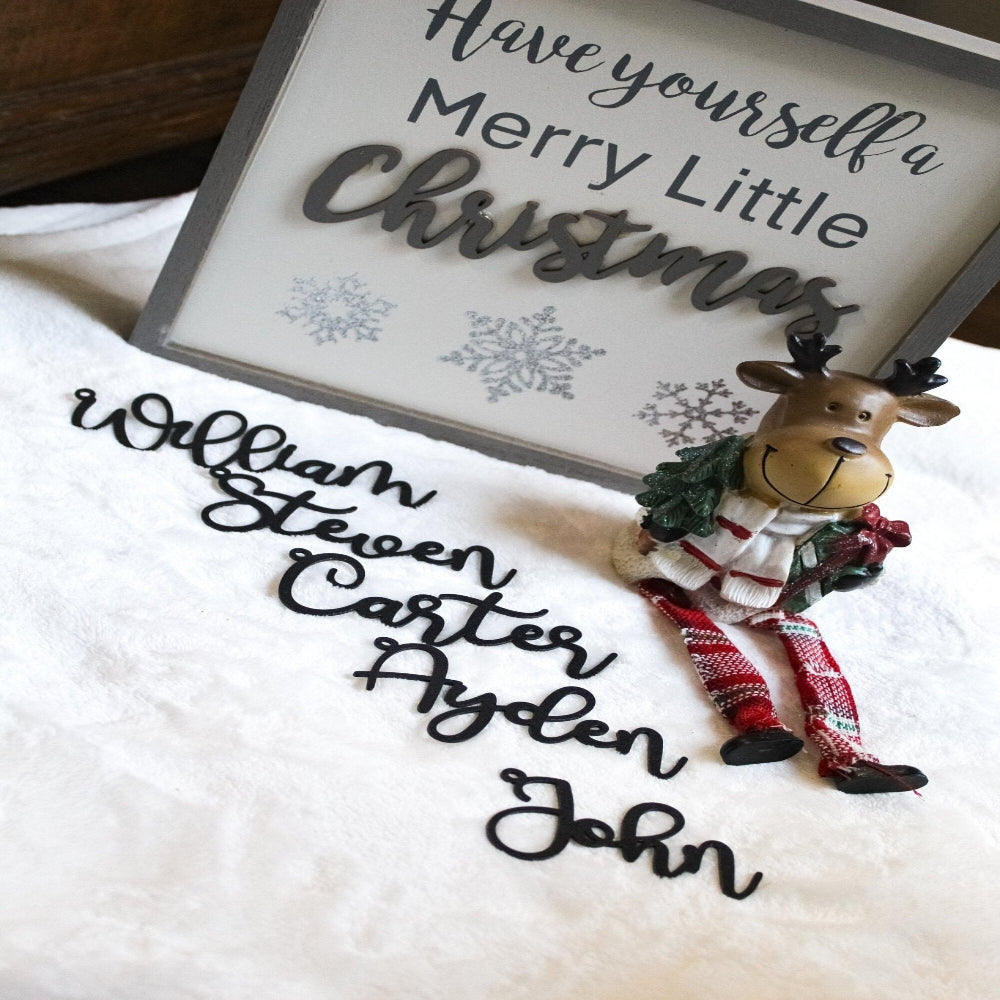 Decorative sign with Have yourself a Merry Little Christmas text and small reindeer figurine on white surface, festive holiday décor for seasonal home display
