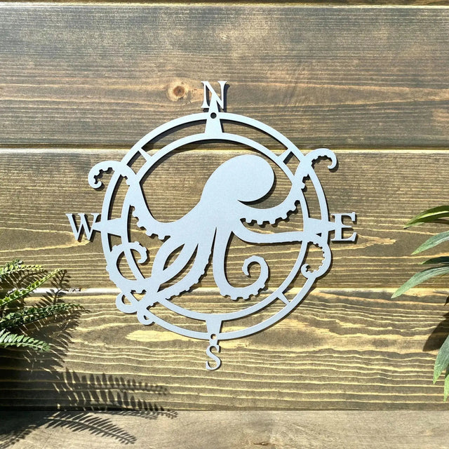 Shiny chrome circular compass sign with stylized octopus, arms point west and east, bold accent for front door or patio.
