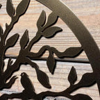 Decorative metal wall art with tree branches and bird design on wooden background, custom outdoor décor, nature-inspired home exterior accent