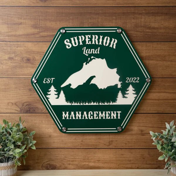 Hexagonal metal sign displaying the “Superior Land Management” logo mounted on a wooden wall, showcasing rustic design and professional branding.