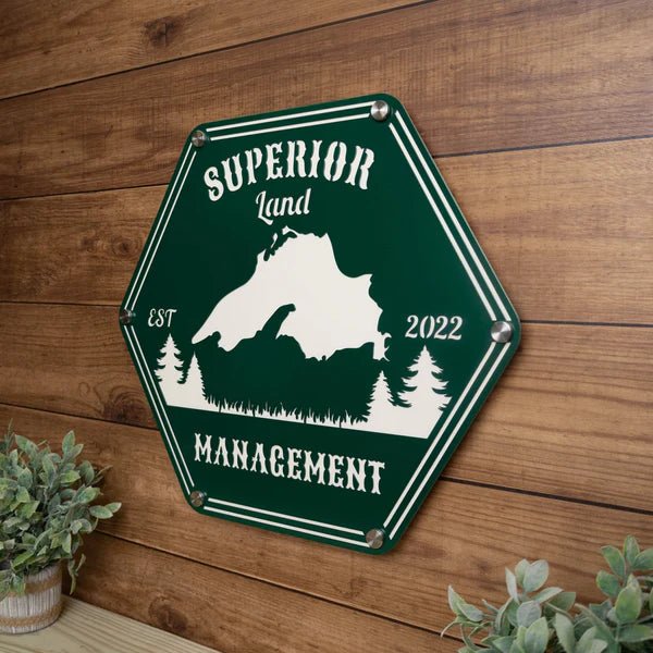 Hexagonal metal sign featuring “Superior Land Management” displayed on a wooden background, highlighting rustic design and durable craftsmanship.