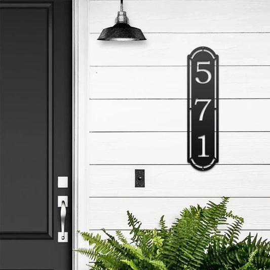Vertical black home address sign with number '571', mounted on door wall.