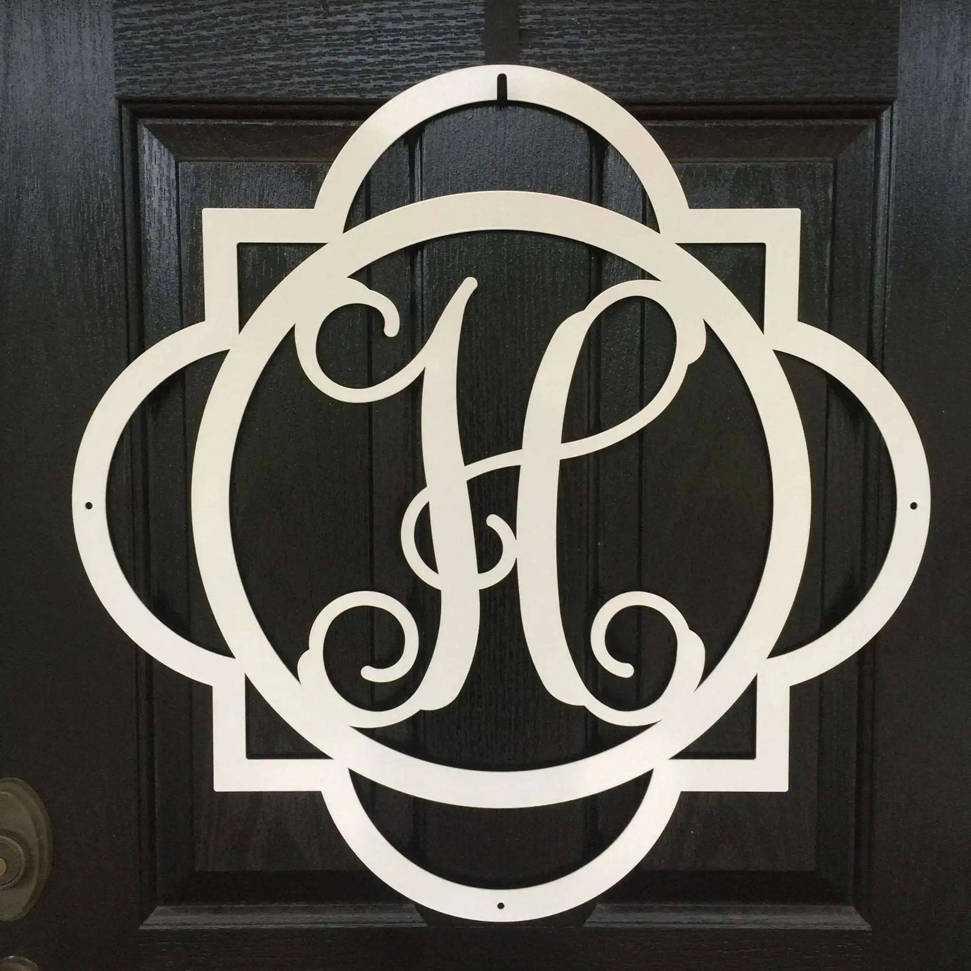 Close-up of white "H" metal monogram door wreath – detailed cutout initial hanger for front door.
