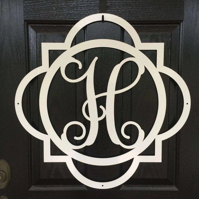 Close-up of white "H" metal monogram door wreath – detailed cutout initial hanger for front door.