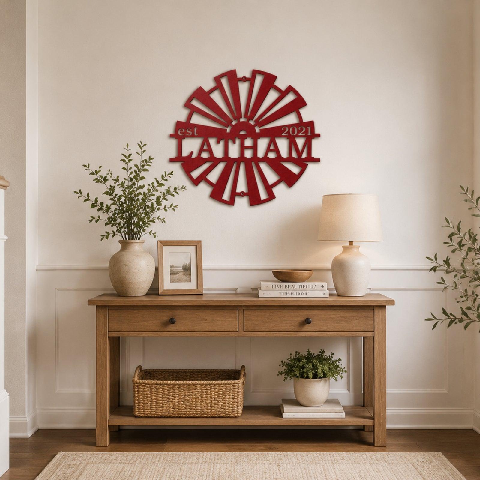 Red personalized windmill metal wall decor with "Latham est 2021" nameplate, hanging above a light wood console table in a minimalist farmhouse entryway.