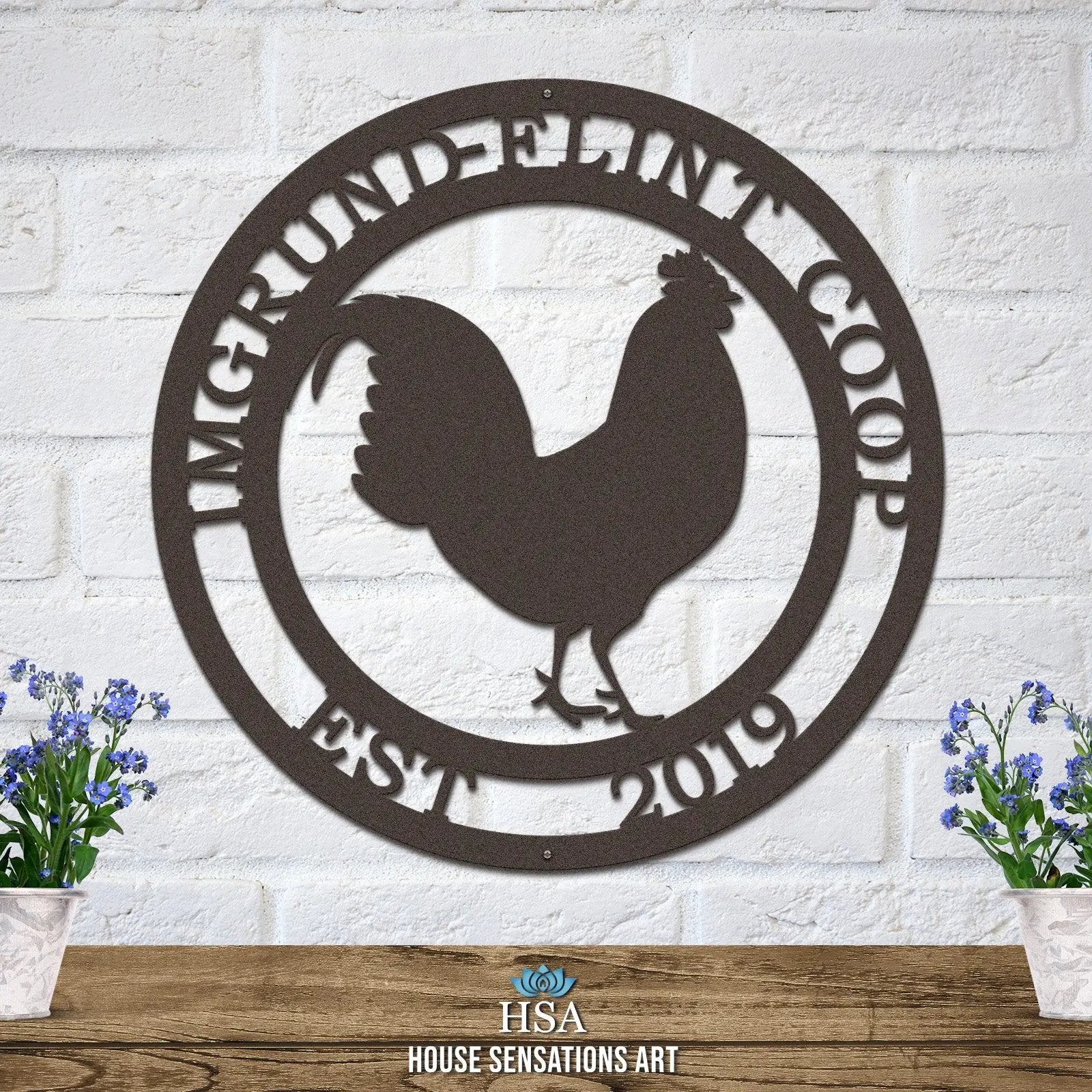 Candy copper circular ranch metal sign with cut-out rooster and “IMGRUND-FLINT COOP EST. 2019” text on brick wall.