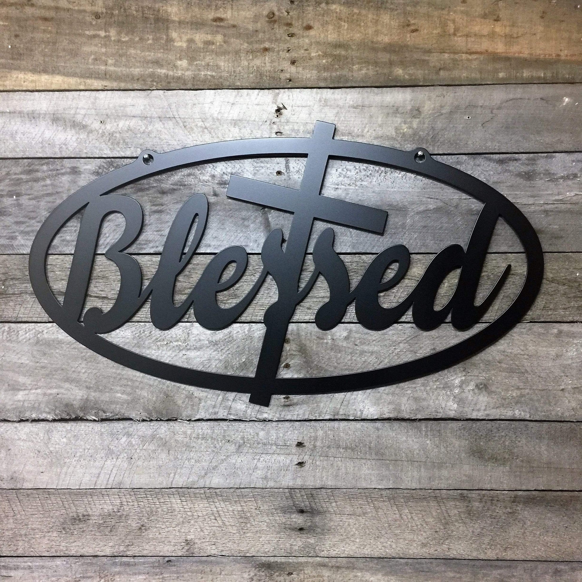 Blessed Sign Established Sign - Personalized Family Name Sign in black metal, featuring a cross and bold uppercase letters, elegantly displayed on a textured wood surface. Ideal for home décor and gifts.