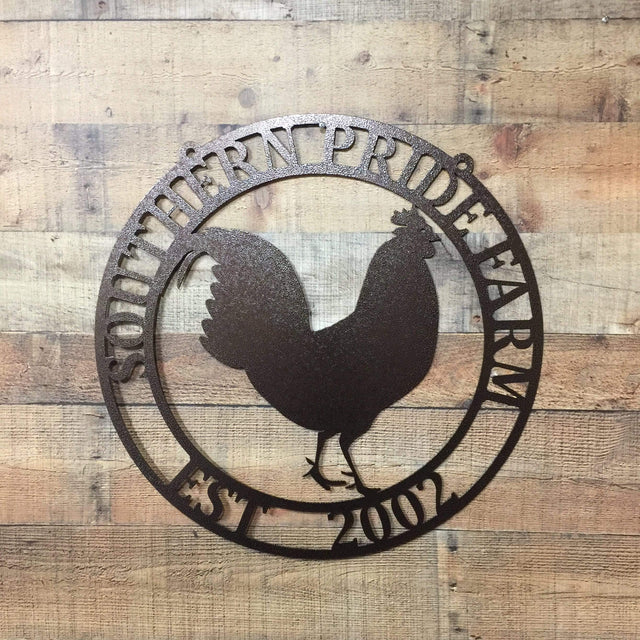 Oil rubbed bronze circular ranch metal sign with rooster cutout and “SOUTHERN PRIDE FARM EST. 2002” on brick wall.