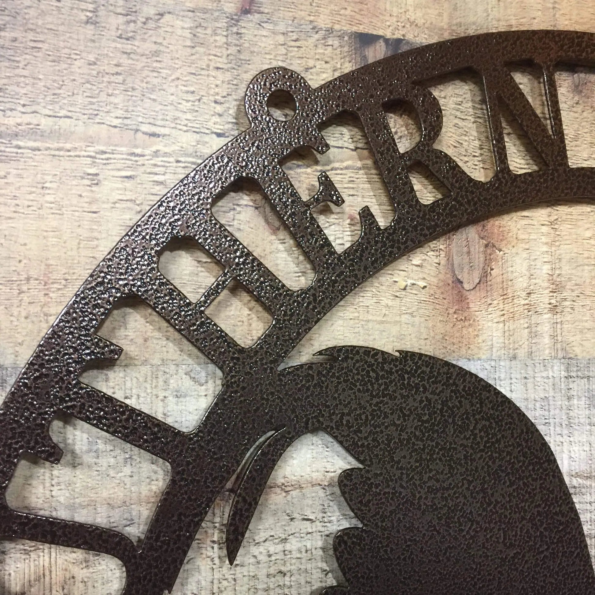 Close-up of oil rubbed bronze ranch metal rooster sign showing “THERN” text cut detail and rustic metal texture.