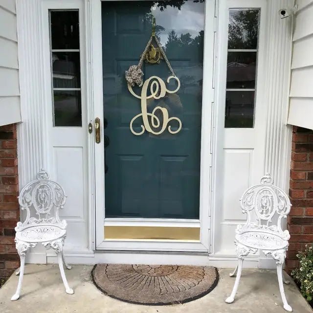 White personalized metal initial door wreath displayed on a bluegreen front door
