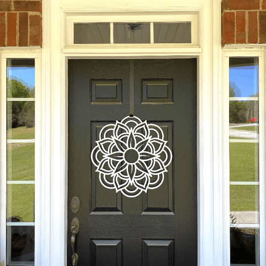 White metal flower wreath on black door, floral wall decor, brick and glass porch entry, modern outdoor metal sign, elegant handcrafted home decor