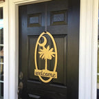 Decorative metal “Welcome” sign with palm tree design on dark wooden door, custom outdoor home entrance décor