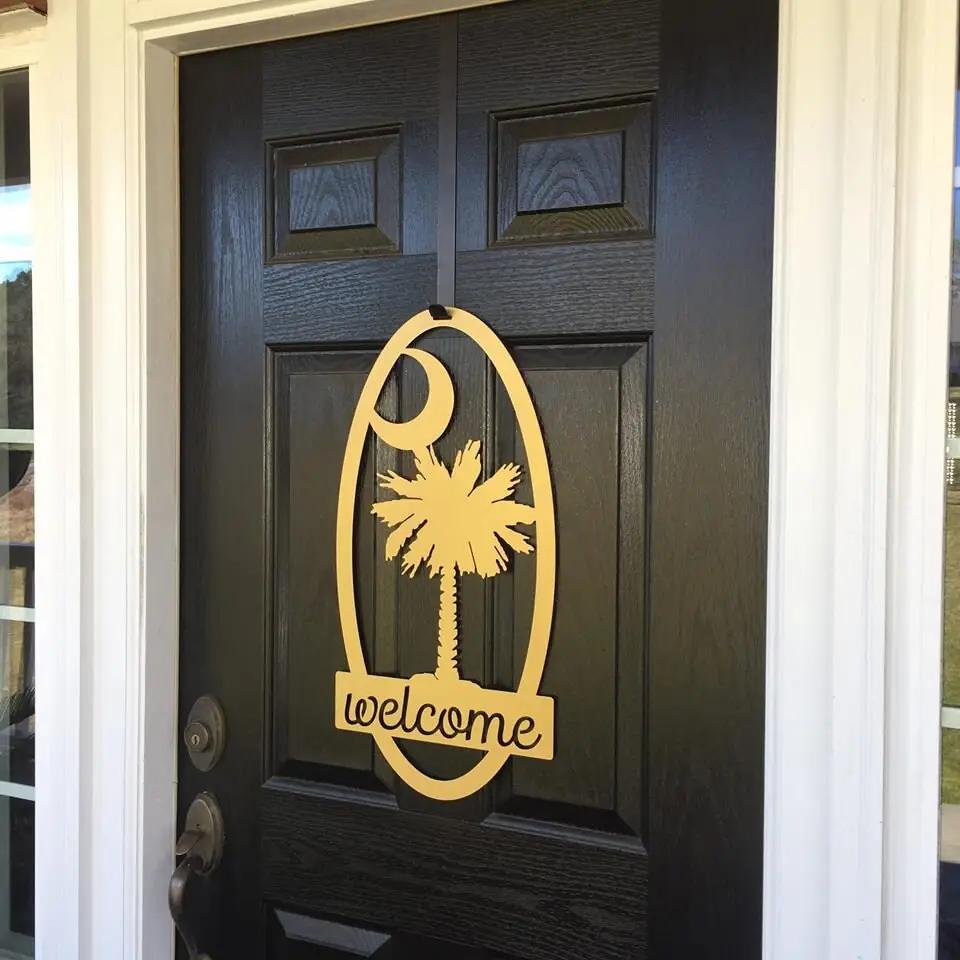 Decorative metal “Welcome” sign with palm tree design on dark wooden door, custom outdoor home entrance décor