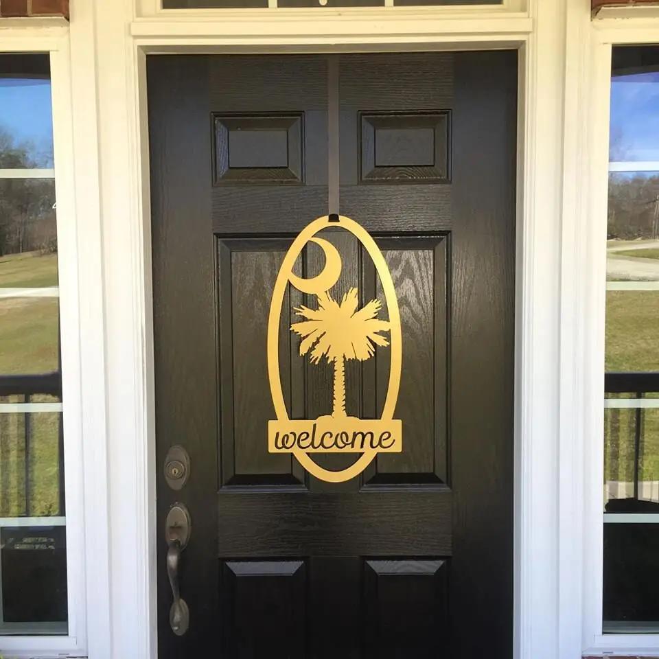 Decorative metal “Welcome” sign with palm tree design on black door, custom outdoor home entrance décor