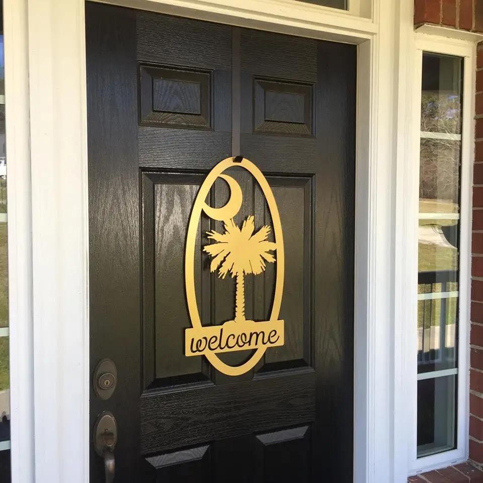 Decorative metal “Welcome” sign with palm tree design on black door, custom outdoor home entrance décor