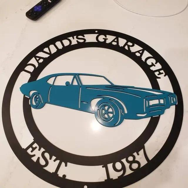 Custom blue car metal wall sign, personalized “David's Garage East 1987” front door décor, powder coated outdoor garage sign, automotive-themed wall art on white background, modern custom steel sign for home or workshop