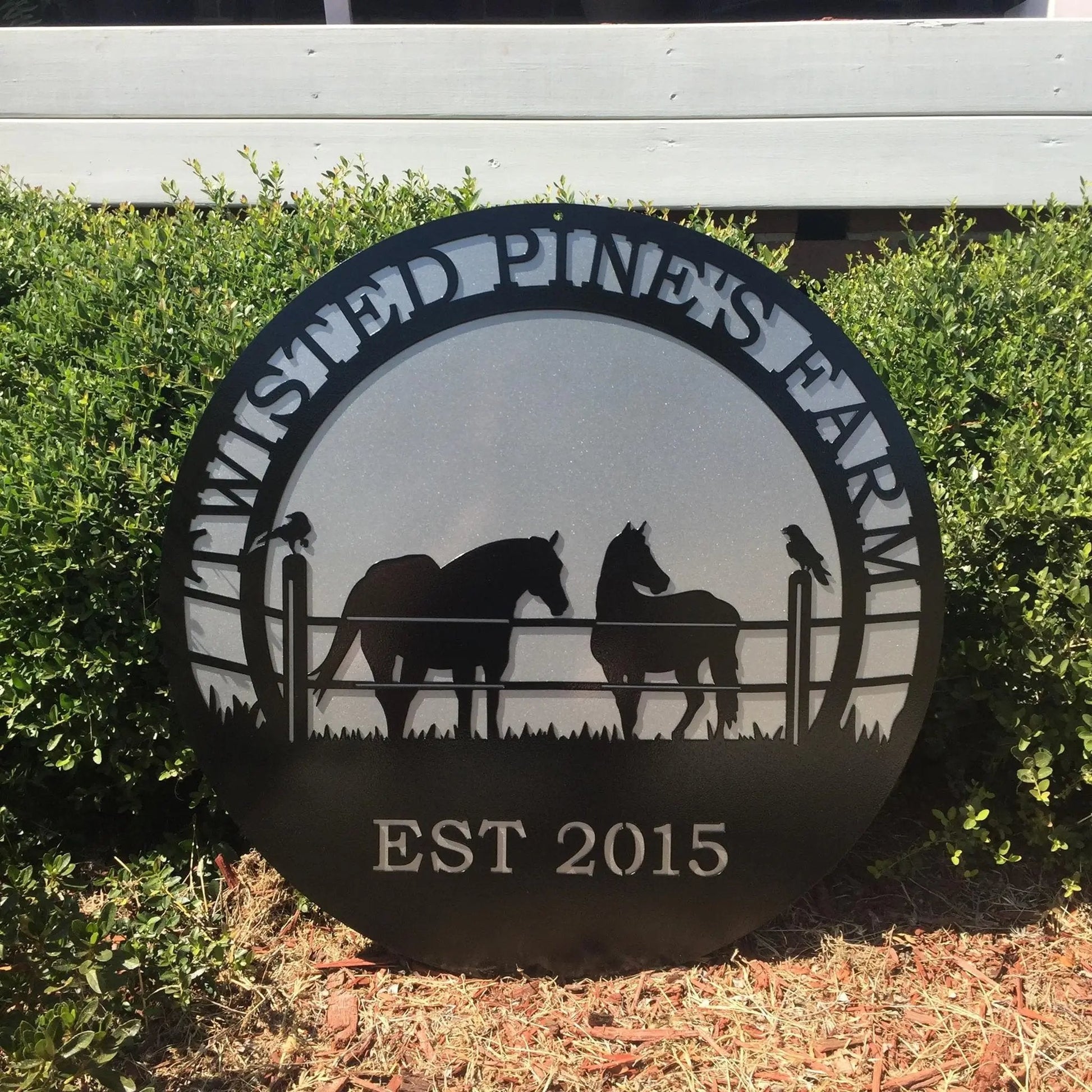 A black custom laser cut metal ranch sign showing horses in pasture with silver background, “TWISTED PINE’S FARM EST 2018” text.