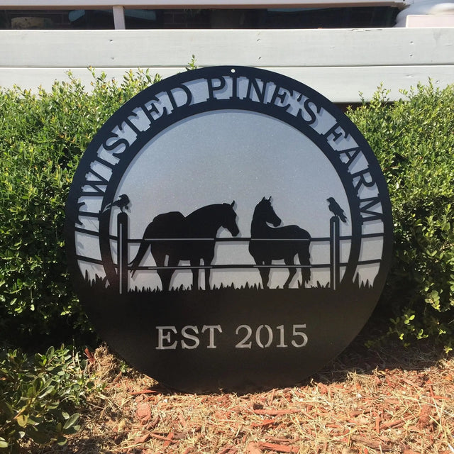 A black custom laser cut metal ranch sign showing horses in pasture, with “TWISTED PINE’S FARM EST 2015” text, placed outdoors.