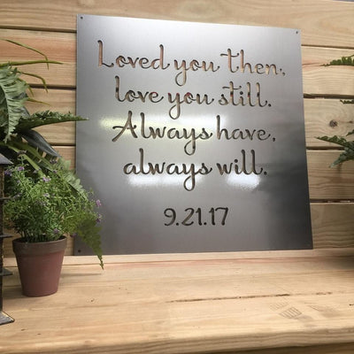 Metal plaque featuring engraved text, displayed on a wooden surface with plants, showcasing personalized design, rustic charm, and durable craftsmanship.