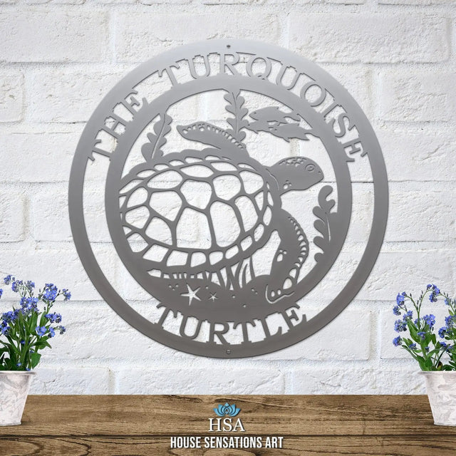 Polished chrome custom laser cut metal sign showing turtle, seaweed, and fish, with “THE TURQUOISE TURTLE” text, mounted on brick wall.