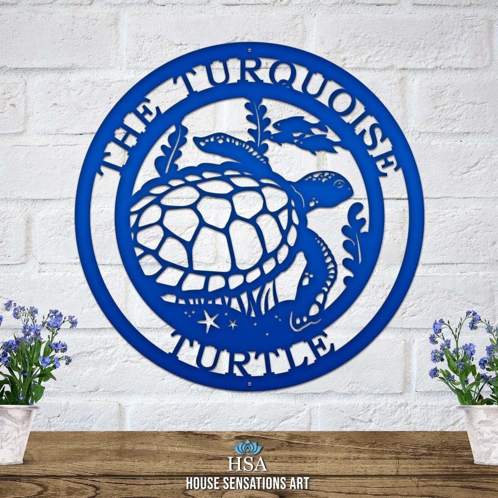 Bright blue custom laser cut metal sign showing turtle, seaweed, and fish, with “THE TURQUOISE TURTLE” text, mounted on a brick wall.