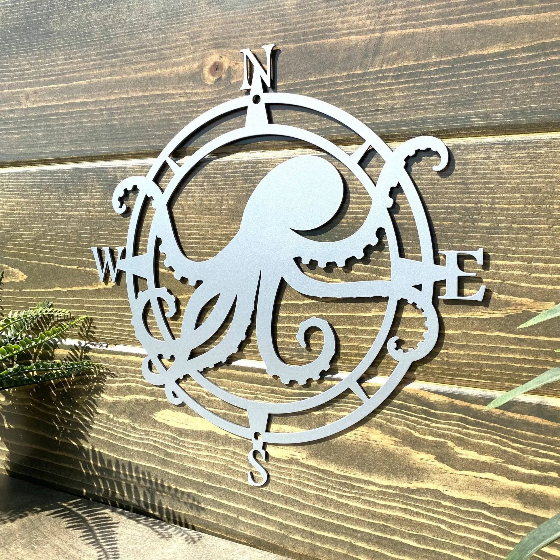 Chrome finish compass-style metal decor with an octopus centerpiece, tentacles highlight W/E, perfect for nautical entryways.